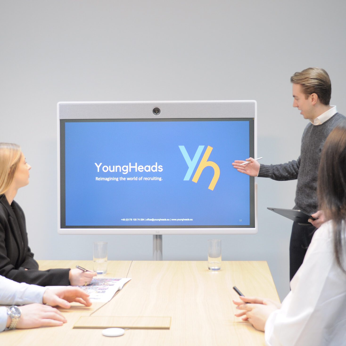 YoungHeads Team in einer interaktiven Session, Logo sichtbar im Hintergrund.